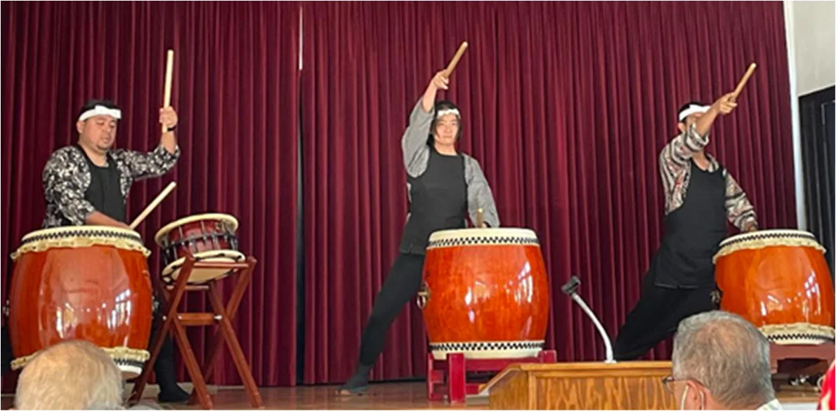 Three taiko performers play large drums on the Social Hall stage during HJCI’s seventy-fifth anniversary celebration.