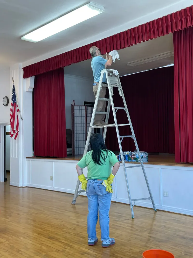 People actively caring for the stage area inside the HJCI Social Hall.
